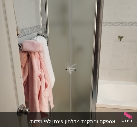 דלת מקלחון עם מגבות ורודות על הקיר